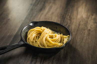 暗色木纹桌面上放着一盘煮熟的意大利面