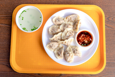 桌面上白色圆盘子里的饺子与清汤