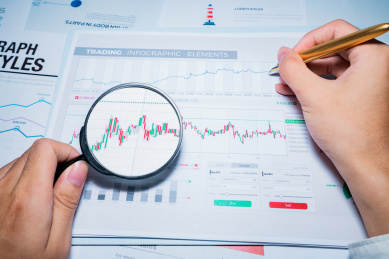 一个金融人士拿着放大镜观察金融图表报表报告数据