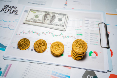 桌面上放着计算器和美美金金币硬币报表图表报告金融经济行情分析概念