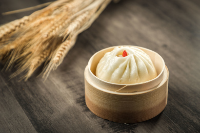 棕色木纹桌面上放着一屉蒸包子