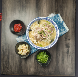 棕色木纹桌面上放着一份羊肉泡馍套餐