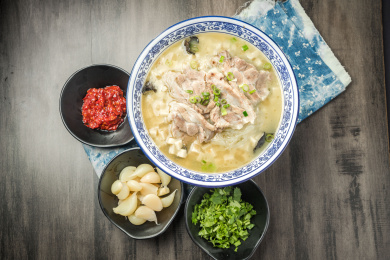 棕色木纹桌面上放着一份羊肉泡馍套餐