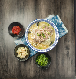 棕色木纹桌面上放着一份羊肉泡馍套餐