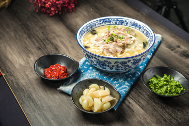 棕色木纹桌面上放着一份羊肉泡馍套餐