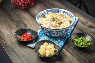 棕色木纹桌面上放着一份羊肉泡馍套餐