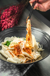 手拿筷子挑起桌上的一碗油泼拌面的面条