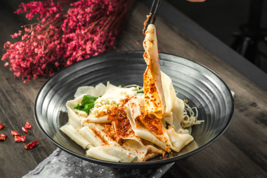 手拿筷子挑起桌上的一碗油泼拌面的面条