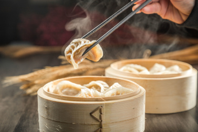 棕色木纹桌面上放着一份冒着热气的蒸饺