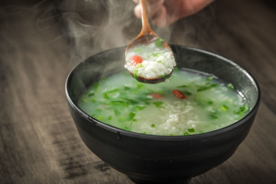 棕色木纹桌面上放着一份冒着热气的菜粥