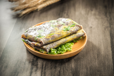 暗色木纹卓上放着一盘紫米面的煎饼