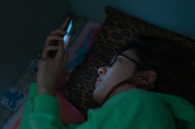 夜里黑灯瞎火关灯黑暗中玩手机的中国近视眼女人