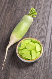 保健蔬菜青萝卜片盛放在盘子中摆放在桌面上