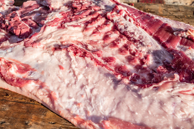 新鲜宰杀的半边猪肉在木案板上