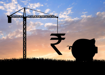 黄昏前剪影效果的草地上吊塔吊起卢比符号准备放进小猪存钱罐里