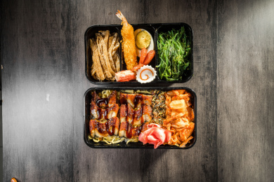 暗色木纹卓上放着一份烤鳗鱼与辣白菜日料米饭套餐