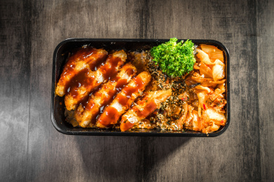 暗色木纹卓上放着一份炸猪排酸菜日料米饭套餐