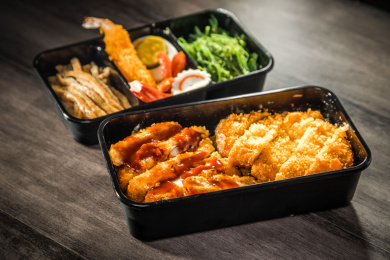 暗色木纹卓上放着一份炸猪排与鸡排双拼日料米饭套餐