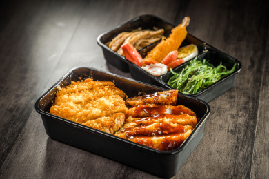暗色木纹卓上放着一份炸猪排与鸡排双拼日料米饭套餐