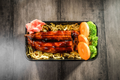 暗色木纹卓上放着一份烤鳗鱼日料米饭套餐