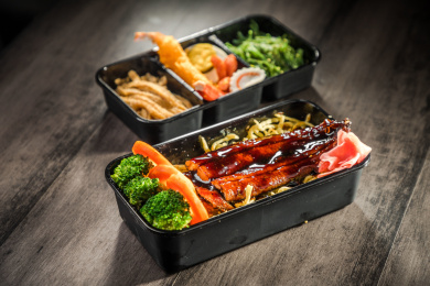 暗色木纹卓上放着一份烤鳗鱼日料米饭套餐