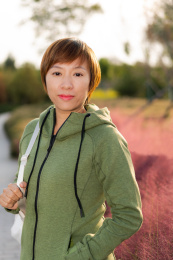 年轻的中国籍女性站在公园的粉黛子花丛前