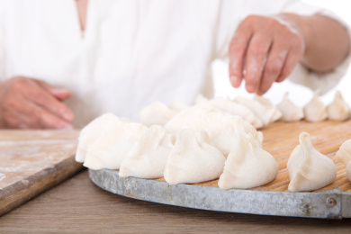 中国妇女正把包好的饺子放在圆形托盘上