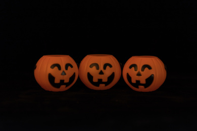 黑色背景上摆放三个笑脸鬼脸南瓜灯