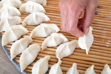 一只手把包好的饺子放在圆形托盘上