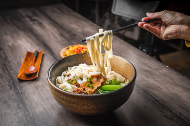 暗色木纹卓上放着一碗炒肉片米粉