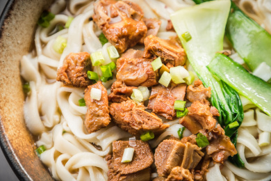 暗色木纹卓上放着一碗炖牛腩米粉