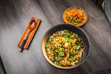 暗色木纹卓上放着一碗青椒炒鸡蛋米粉