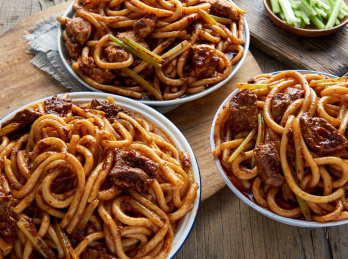 木桌背景下的三盘新疆特色牛肉炒米粉