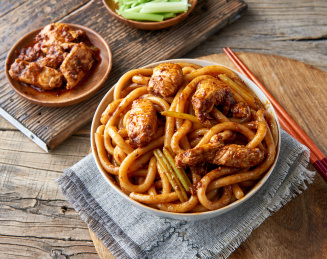 木桌背景下盘中的新疆特色鸡肉炒米粉