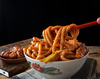 深色背景下盘中的新疆特色鸡肉炒米粉