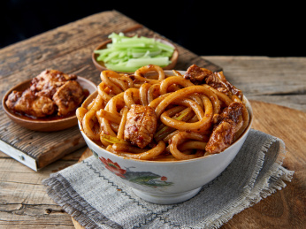 木桌背景下盘中的新疆特色鸡肉炒米粉