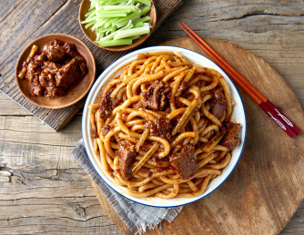 木桌背景下盘中的新疆特色牛肉炒米粉