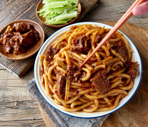 木桌背景下盘中的新疆特色牛肉炒米粉