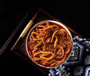 深色背景下盘中的新疆特色牛肉炒米粉