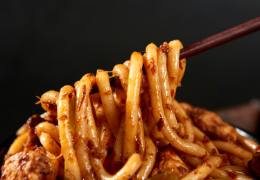 深色背景下筷子夹的新疆特色鸡肉炒米粉