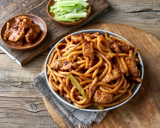 木桌背景下盘中的新疆特色鸡肉炒米粉