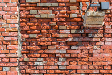 太阳光斜照在一面残损的凹凸不平的红砖墙上