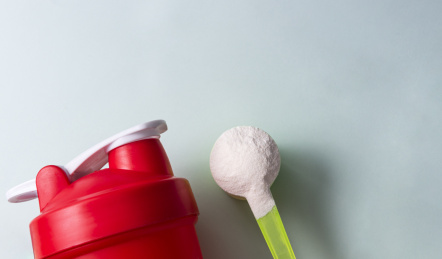 蛋白质营养补充剂，蛋白粉在勺子里和红色的瓶子