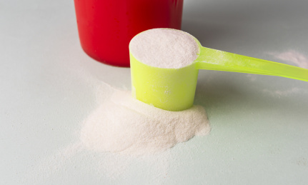 蛋白质营养补充剂，蛋白粉在勺子里和红色的瓶子