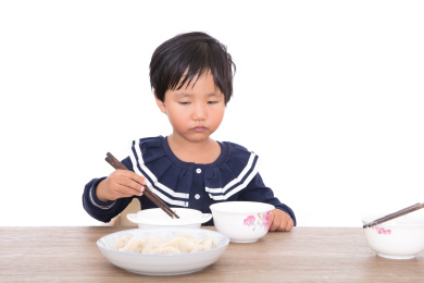 中国小女孩坐在桌子前吃饺子