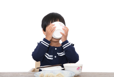 吃饭中的中国小女孩手捧瓷碗喝光了碗里的饺子汤