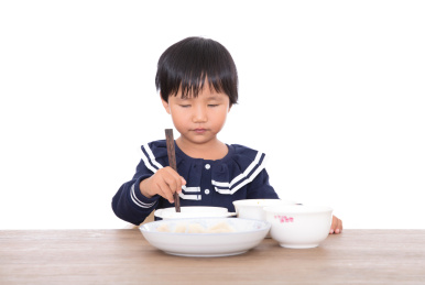 黄皮肤小姑娘在餐桌上仔细的吃饭