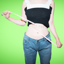 美女拿着皮尺卷尺测量自己的腰围减肥概念