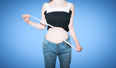 美女拿着皮尺卷尺测量自己的腰围减肥概念