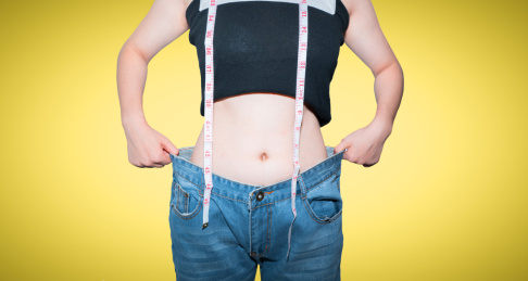 美女拿着皮尺卷尺测量自己的腰围减肥概念